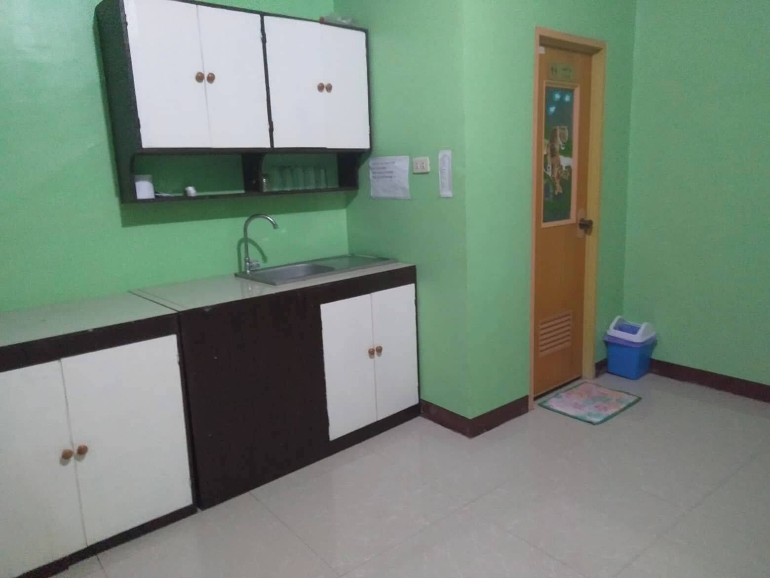 A small kitchen with a sink, cabinets, and a door.