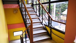 A staircase with a handrail, leading to a room with a window overlooking a garden. - A's Azotea de Bohol (Tagbilaran)