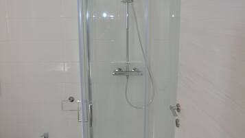 Une salle de bain moderne dotée d’une douche à parois de verre, d’un bidet et d’un sol carrelé.