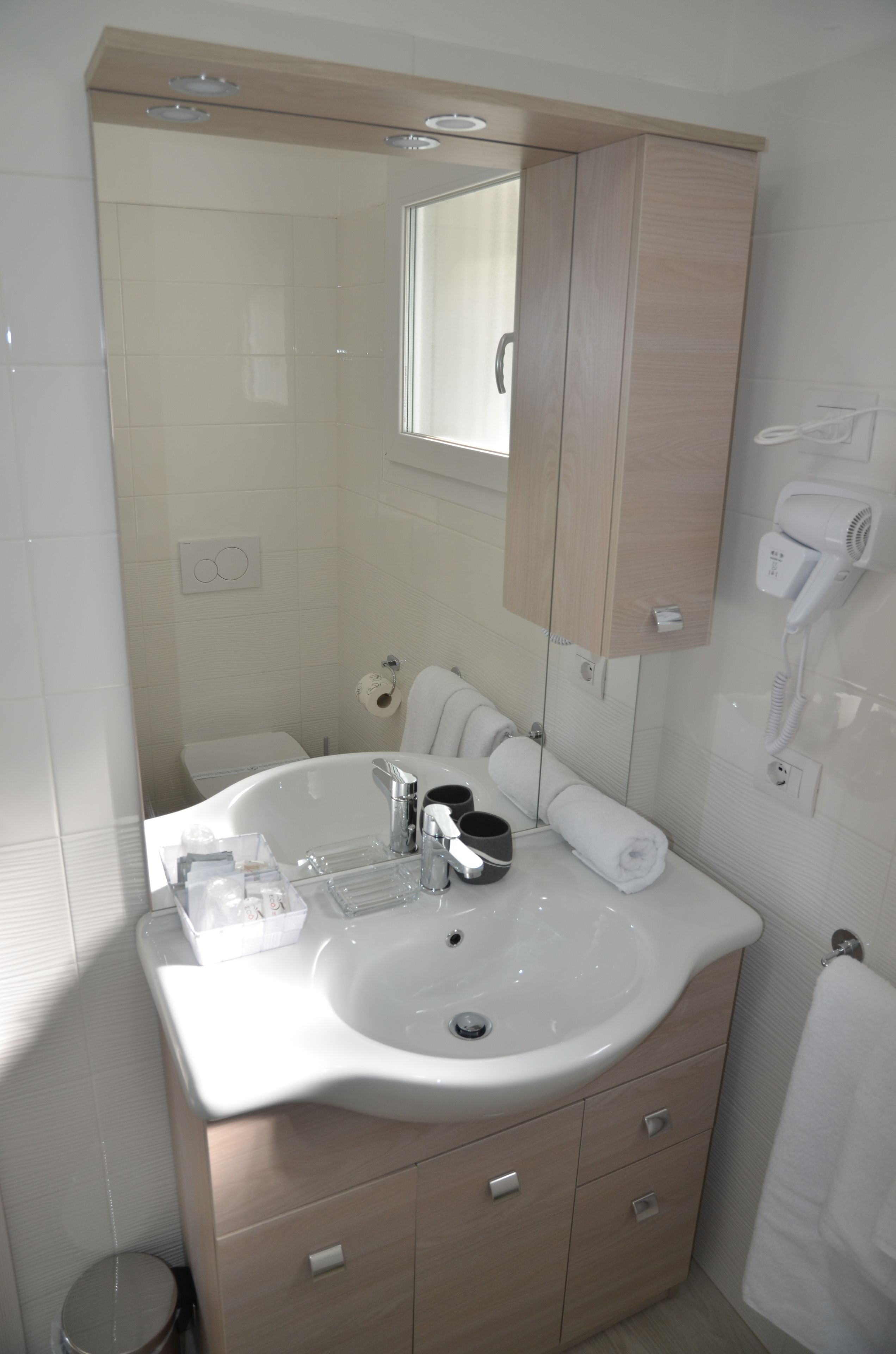 Une salle de bain moderne dotée d’un grand miroir, de deux lavabos, d’un sèche-cheveux et d’un porte-serviettes.