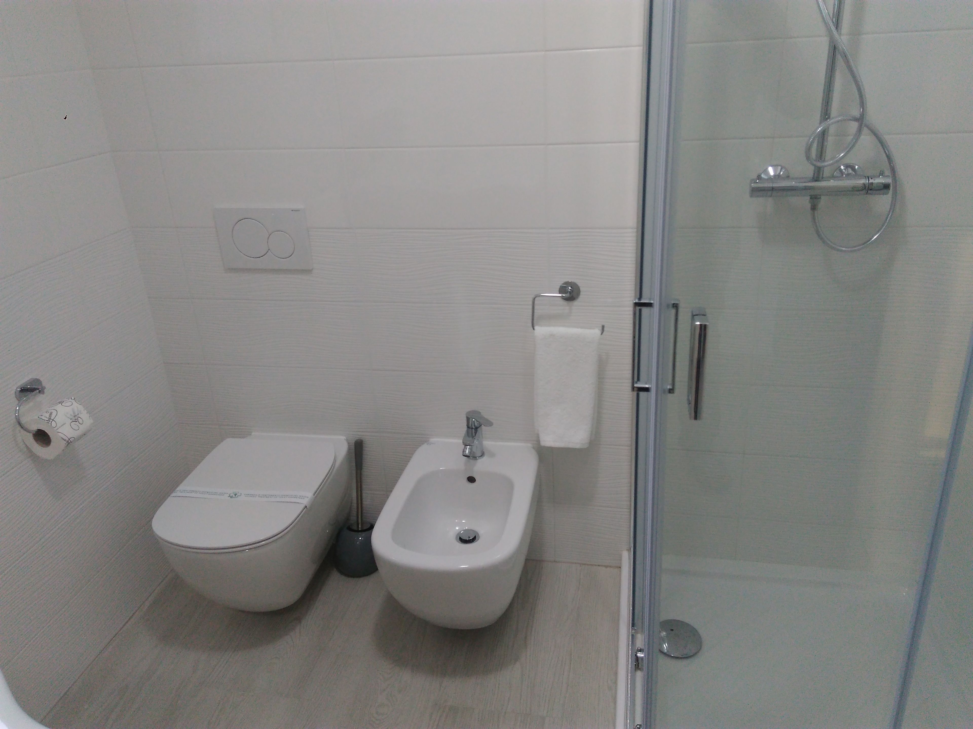 Et moderne badeværelse med toilet, bidet og bruseniche.