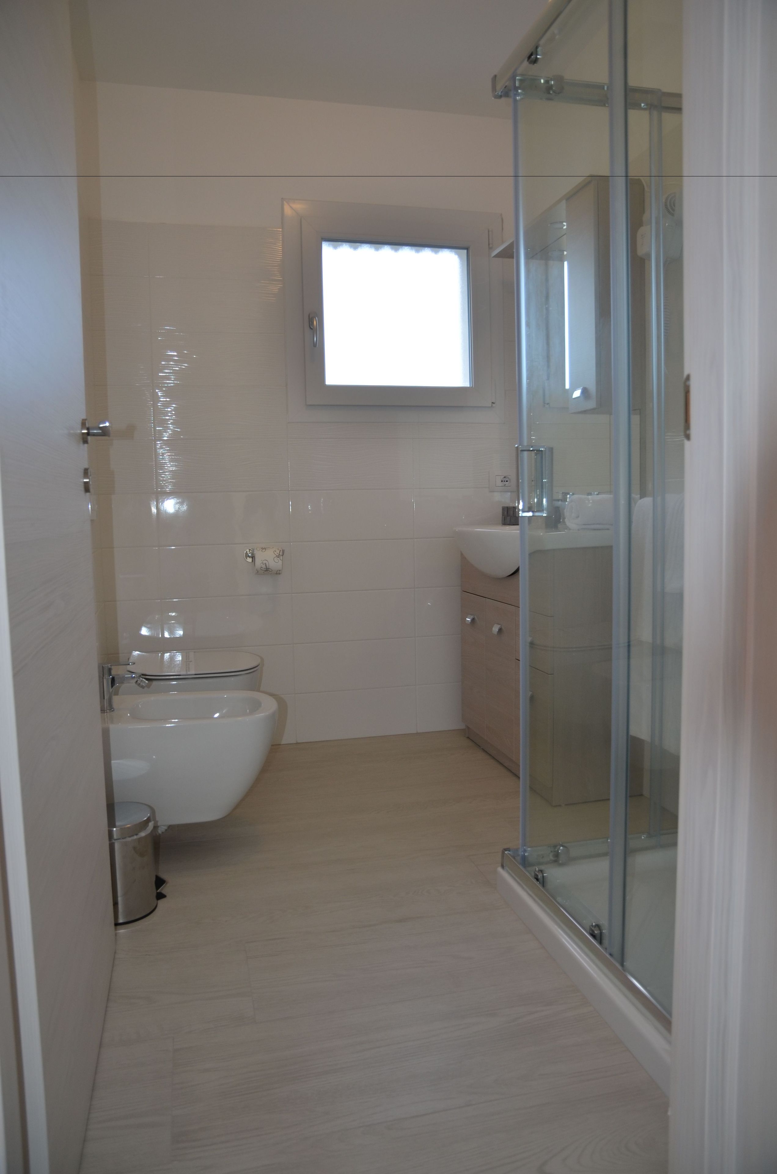 Une salle de bain comprenant des toilettes, un bidet, un lavabo et une douche à parois de verre.