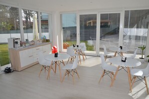 A modern kitchen with white cabinets, a countertop with various items, and a large sliding glass door leading to a patio area with outdoor seating. - Crystal bed and breakfast (Dormelletto)