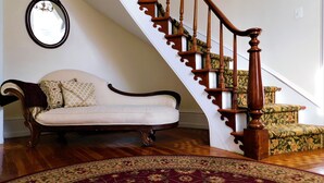 A staircase with wooden balusters, a white sofa with patterned cushions, and a patterned rug on a wooden floor. - The Rosemont Inn (Montrose)