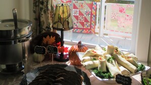 A table with food items, a lamp, and a window with a view of trees and a fence. - The Rosemont Inn (Montrose)