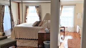 A bedroom with a four-poster bed, wooden beams, a nightstand, and a bedside table with a lamp. - The Rosemont Inn (Montrose)