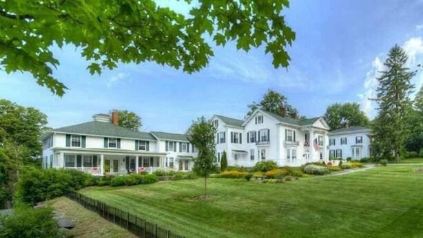 A large, white, multi-story house with a well-maintained lawn and a black metal fence. - The Rosemont Inn (Montrose)