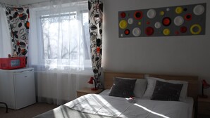 A bedroom with a bed, a nightstand, a red lamp, a white radiator, and a red microwave on a small table. - Privat Voyage (Liptovsky Mikulas)