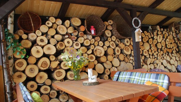 A rustic wooden bench with a plaid cushion, a wooden table, and a vase with flowers. - Privat Voyage (Liptovsky Mikulas)