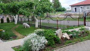 A fenced garden with a sheep, trees, and a building in the background. - Privat Voyage (Liptovsky Mikulas)