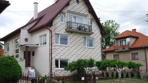 A two-story residential building with a brick facade, a balcony, and a small garden area. - Privat Voyage (Liptovsky Mikulas)