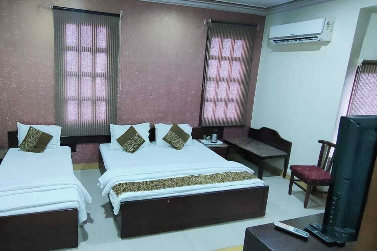 Habitación de hotel con dos camas, un escritorio, una silla, un televisor y un aire acondicionado.