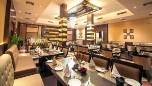 Un restaurant avec des tables hautes, des banquettes confortables et un lustre moderne.