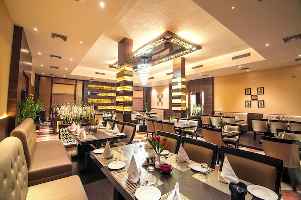 A restaurant with high tables, cushioned booths, and a modern chandelier.