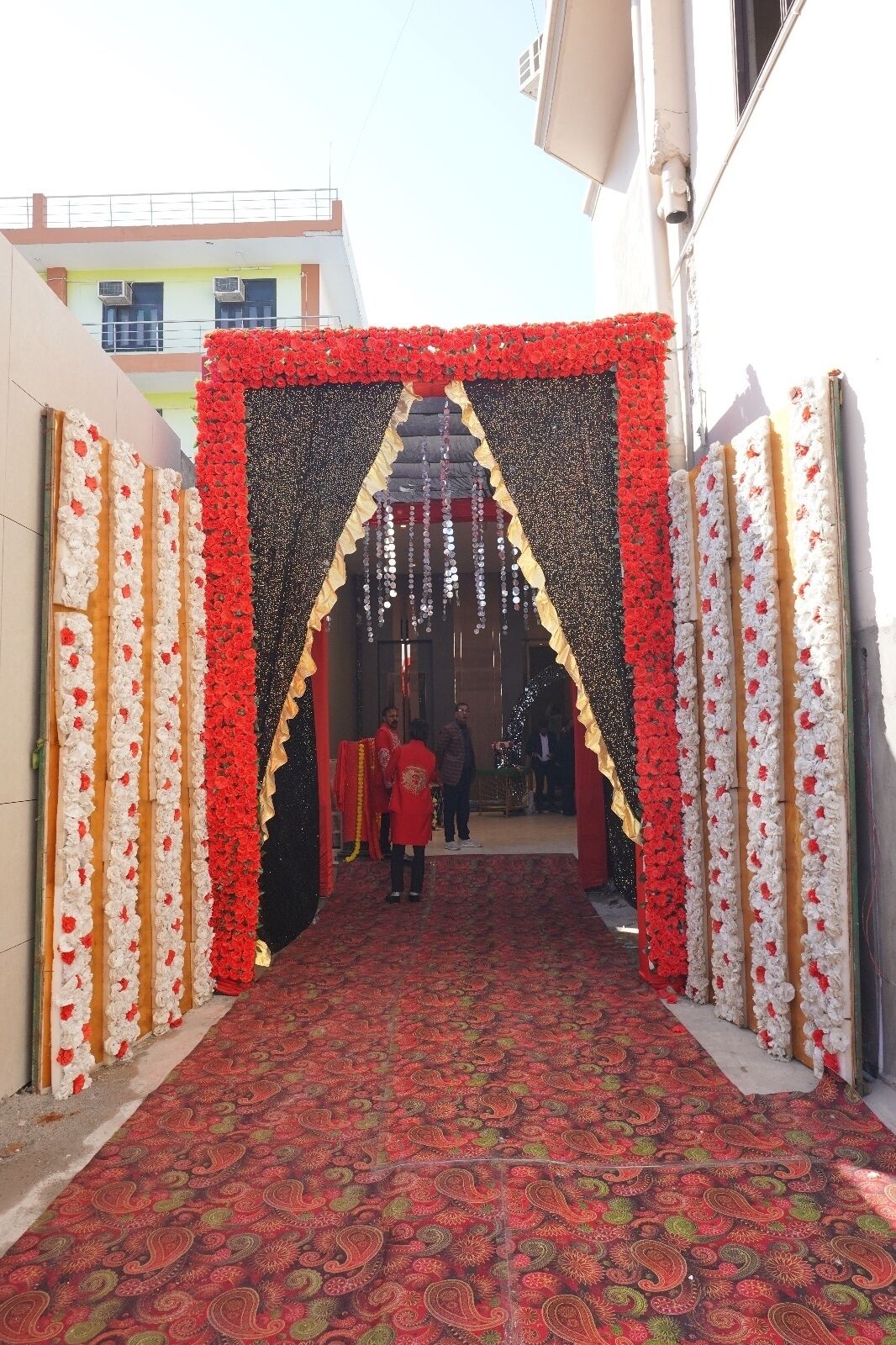 Une entrée agrémentée de compositions florales et recouverte d’un tapis à motifs.
