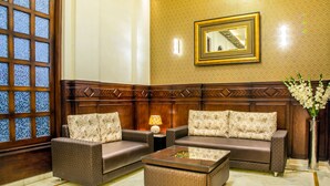 Une pièce avec deux canapés marron, une table basse en verre et un mur décoratif en bois agrémenté d’un miroir.