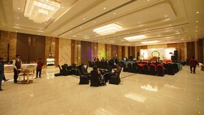 Une vaste salle de banquet dotée d’une scène, de rangées de chaises et d’un plancher ciré.