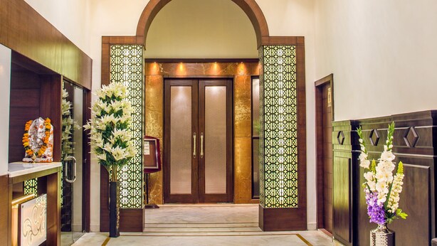 Un hall d’hôtel avec un sol en marbre, un comptoir d’accueil et une grande porte en arc de cercle.
