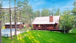 Un rustico chalet con un’ampia veranda, immerso tra alberi e circondato da un prato curato.
