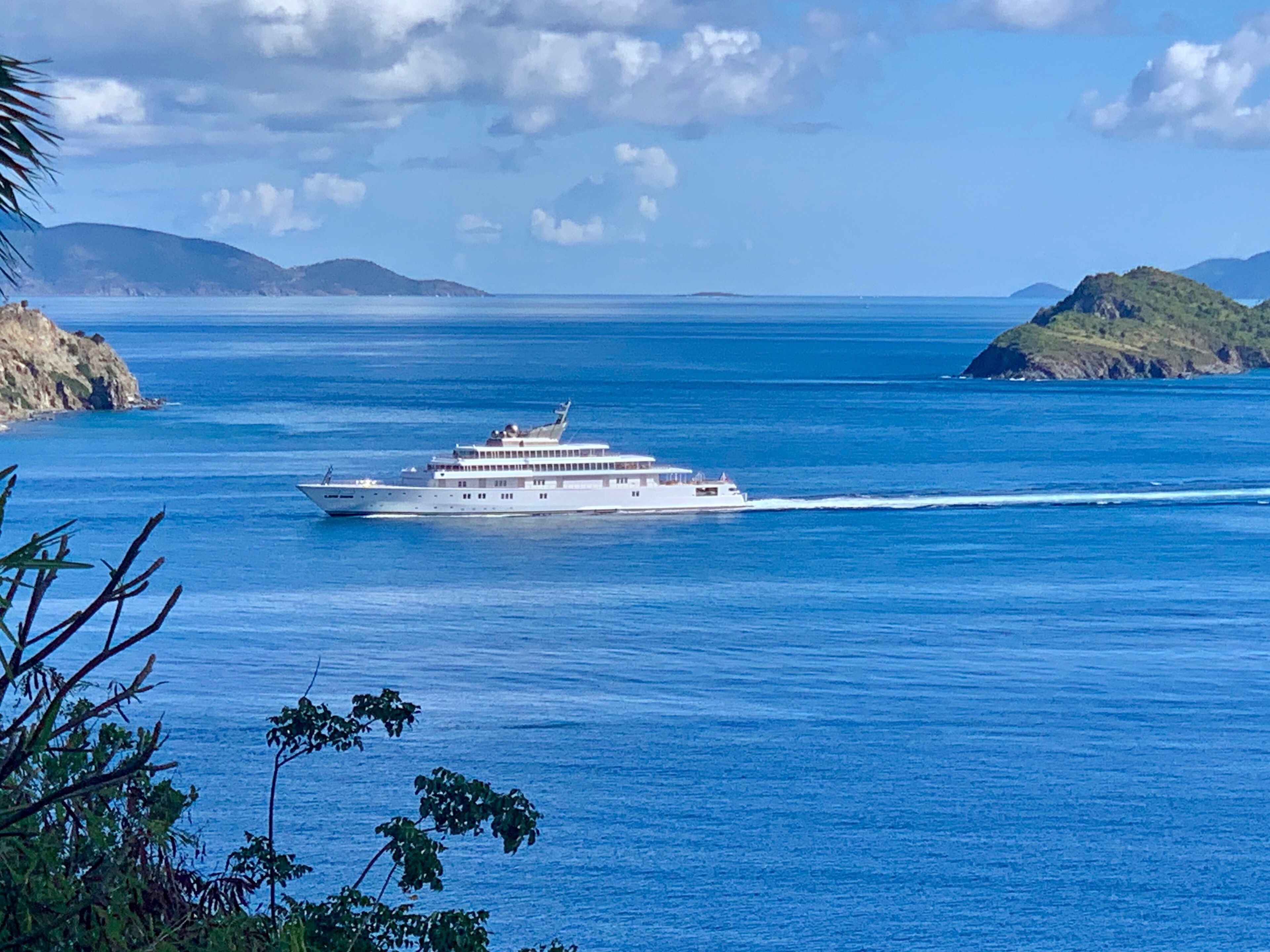 A large cruise ship on a calm sea with distant landmasses.