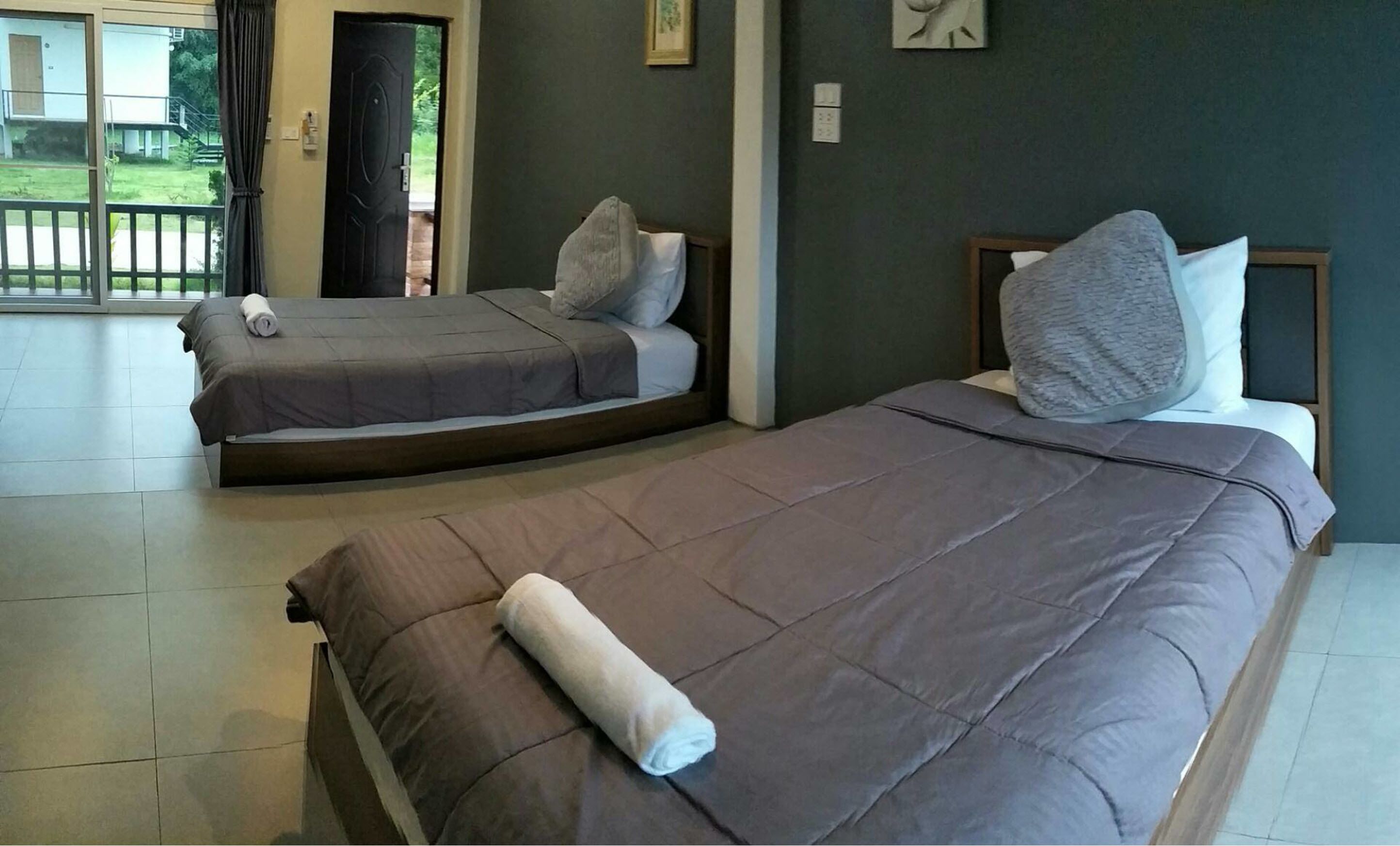 A hotel room with two beds, a large window, and a view of the outdoors.