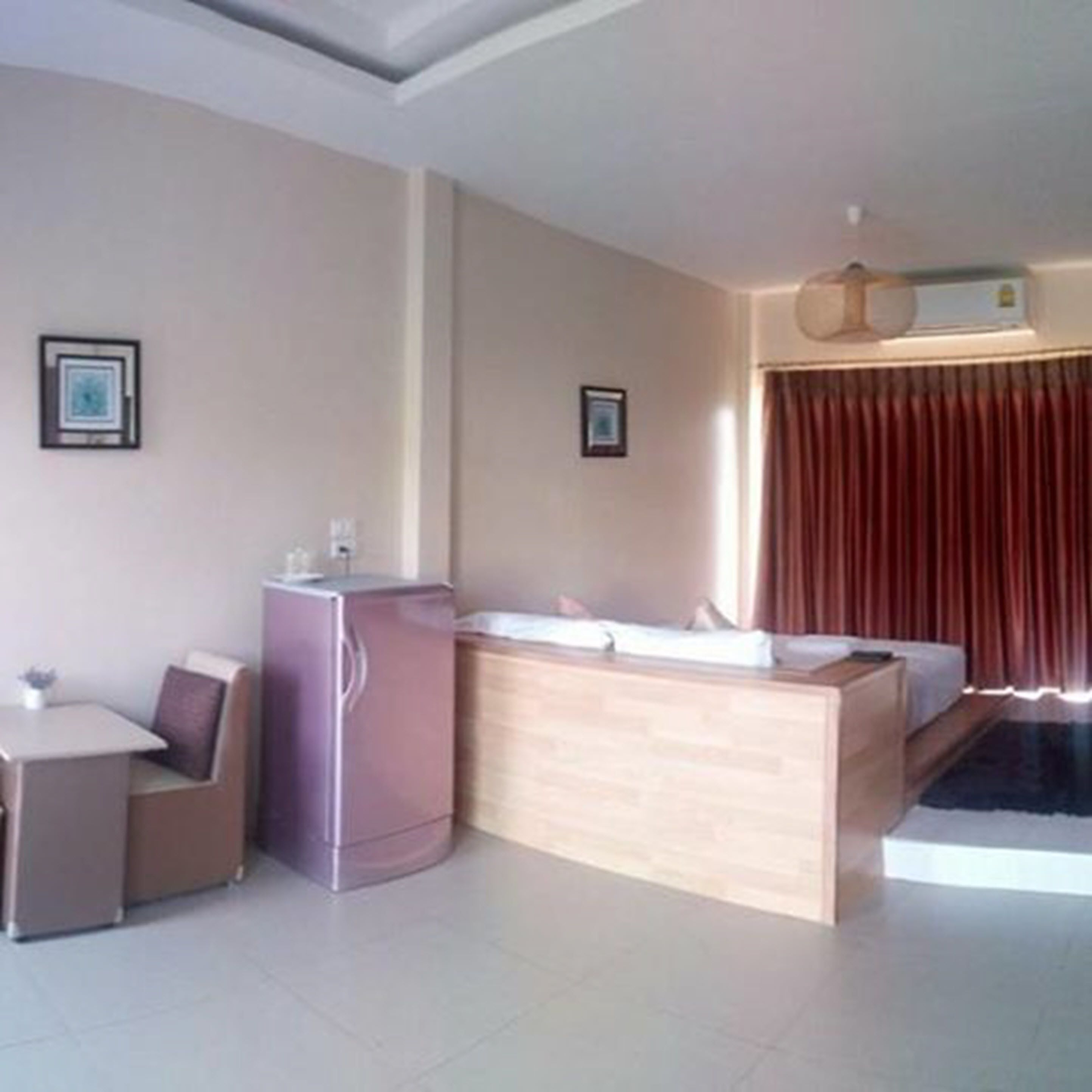 Habitación de hotel compacta con kitchenette, una pequeña mesa de comedor, una cama y un ventanal grande con cortinas.