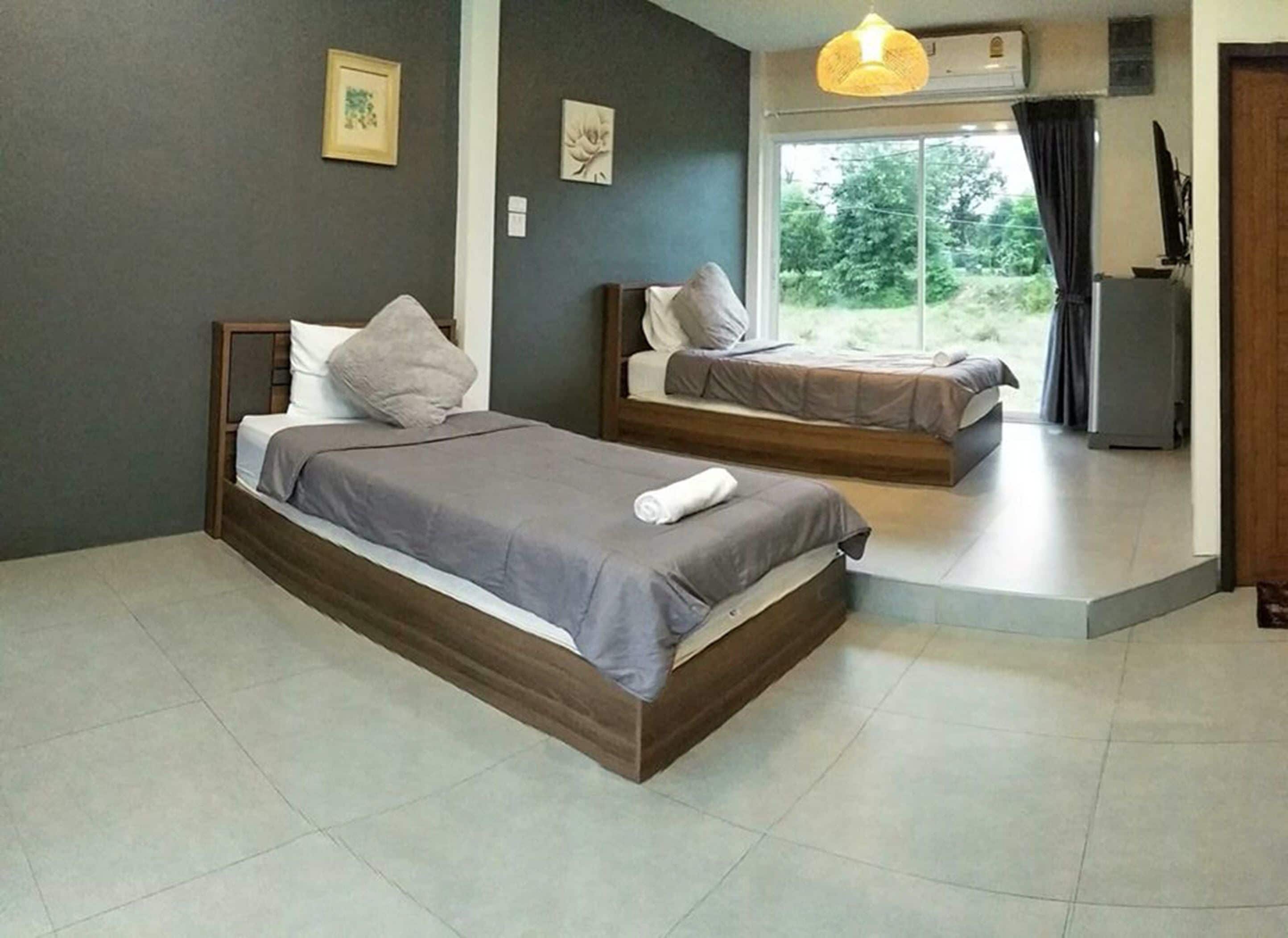 Un dormitorio moderno con dos camas, un ventanal grande y una pequeña kitchenette.