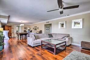 A spacious living room with a wooden floor, a glass coffee table, a grey sofa, and a ceiling fan. - Truly a One of a Kind estate! (Bonita Springs)