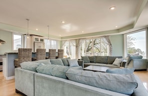 A modern living room with a sectional sofa, wicker chairs, and a dining area. - Beachfront Luxury Home-NEW Private Heated Pool, Lake View, Firepit, Game Room (South Haven)