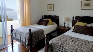 A hotel room with two beds, a large window with curtains, a nightstand with a lamp, and framed pictures on the wall. - Wonderful Penthouse  (Funchal)