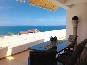 A balcony with a table and chairs, overlooking a coastal view with buildings and the sea. - Wonderful Penthouse (Funchal)