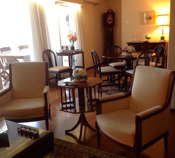 A traditional living room with a dining area, featuring wooden furniture, a clock, and a lamp. - Wonderful Penthouse (Funchal)