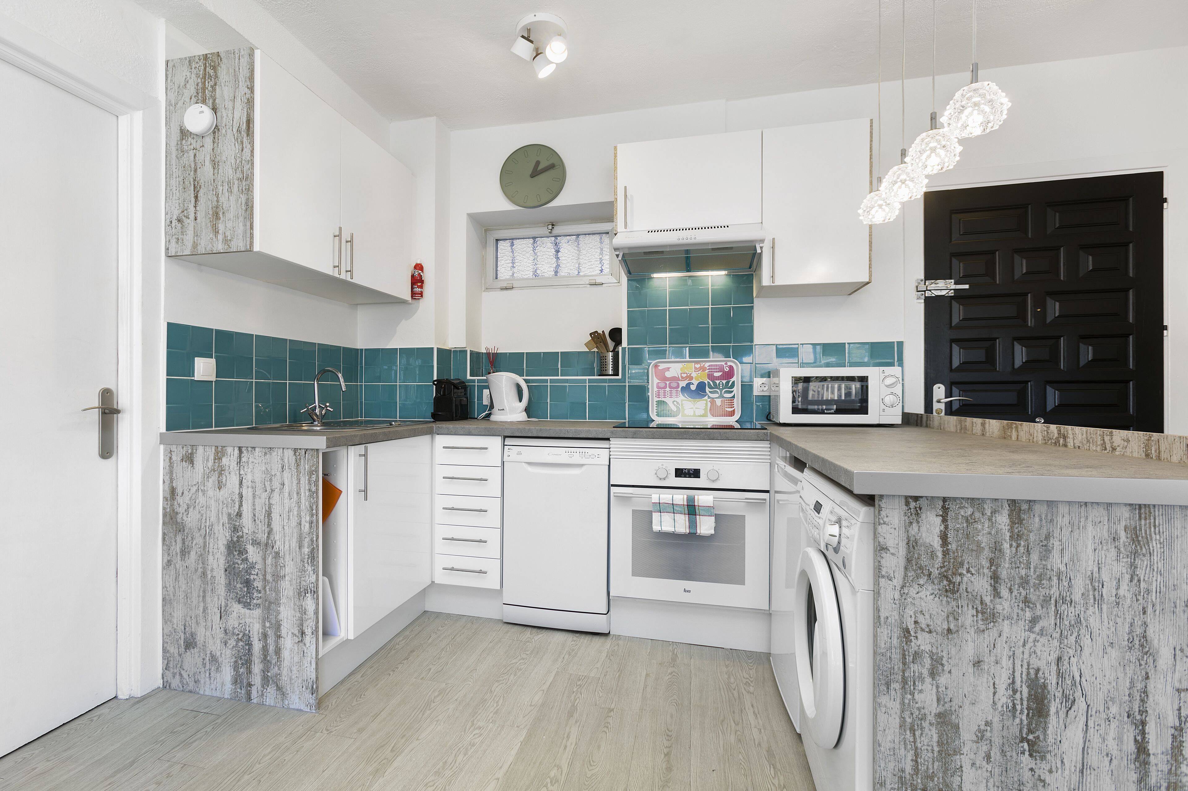 A modern kitchen with white cabinetry, a dishwasher, an oven, a microwave, and a washing machine.