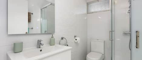 A modern bathroom with a white sink, mirror, and toilet.