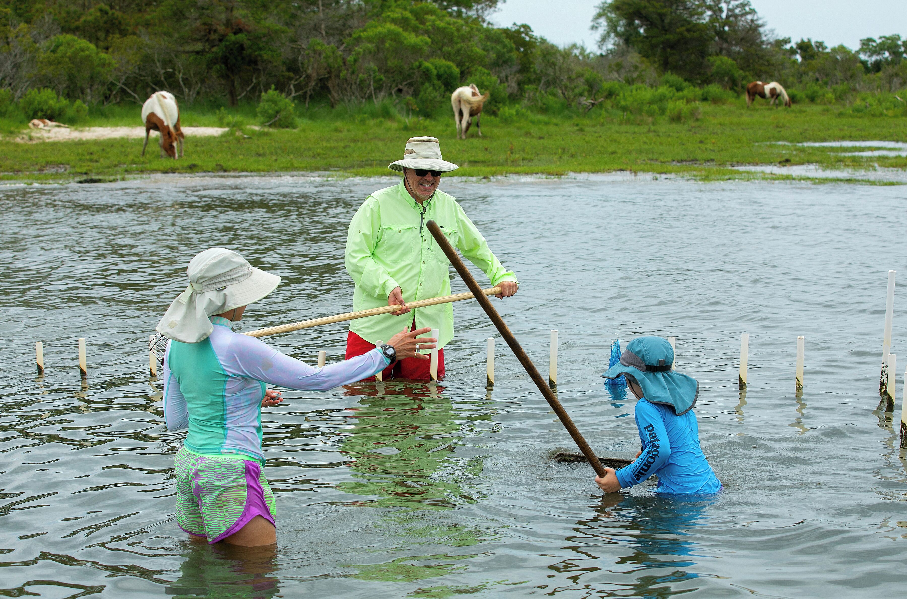 Tres personas en el agua impulsándose con largos palos.