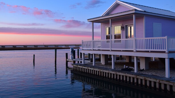 A waterfront house with a balcony, dock, and a view of the water.