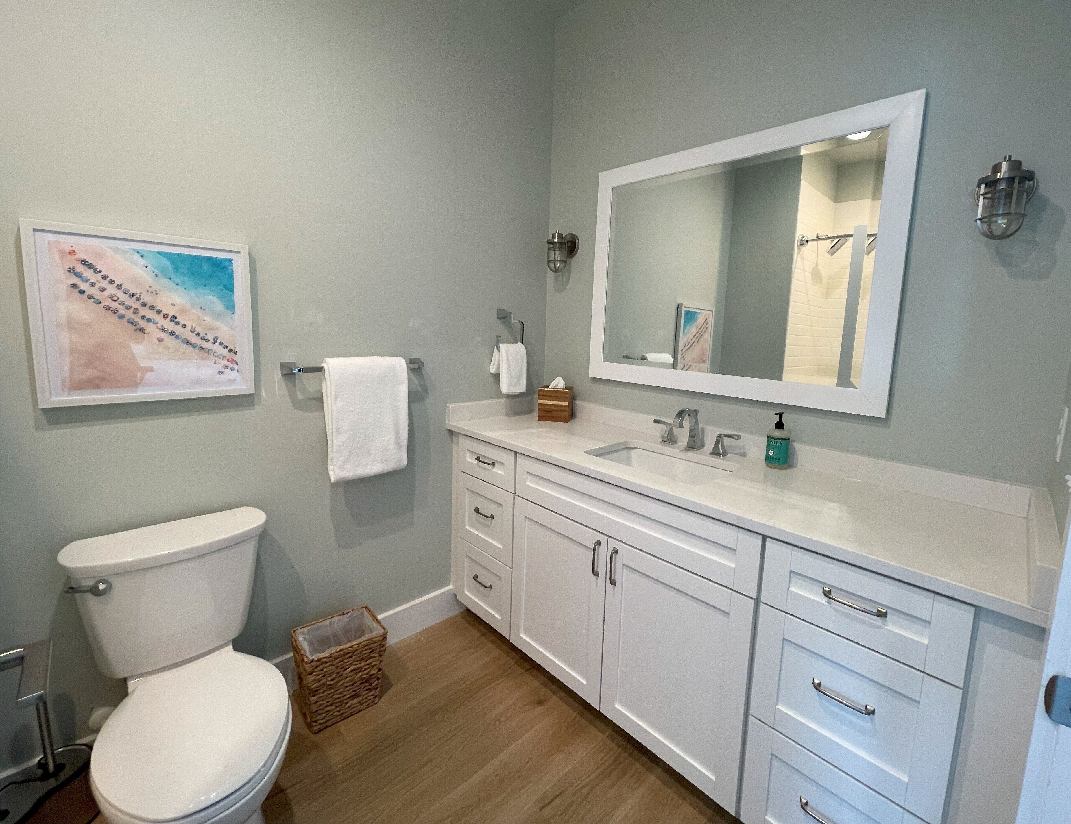 A bathroom with a toilet, a sink, a mirror, and a cabinet.