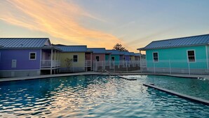 A row of colorful cabins with a swimming pool in the foreground.