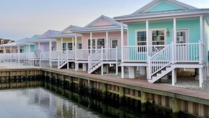 A row of beach houses with white railings and steps leading down to the water.