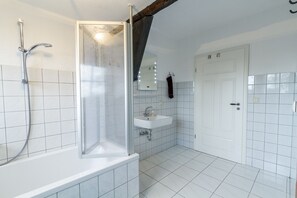 Een bad/douchecombinatie, een haardroger, handdoeken, zeep