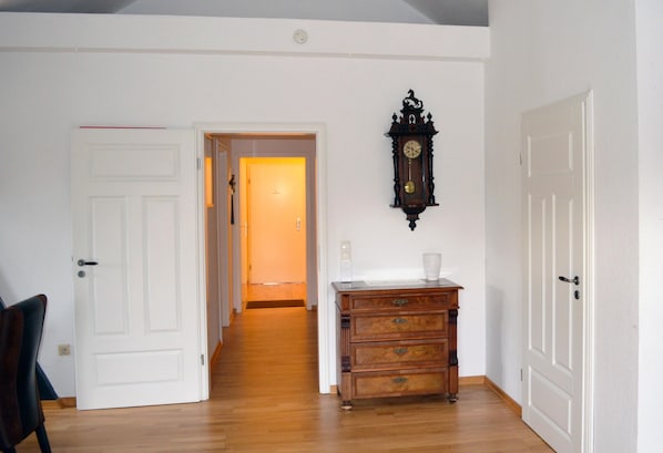 A hallway with wooden flooring, white doors, and a wooden dresser with drawers.