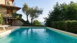 Une piscine avec un bâtiment en pierre et un balcon en bois.