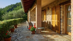 Une terrasse dallée de pierres, agrémentée de meubles en osier et de plantes en pot.