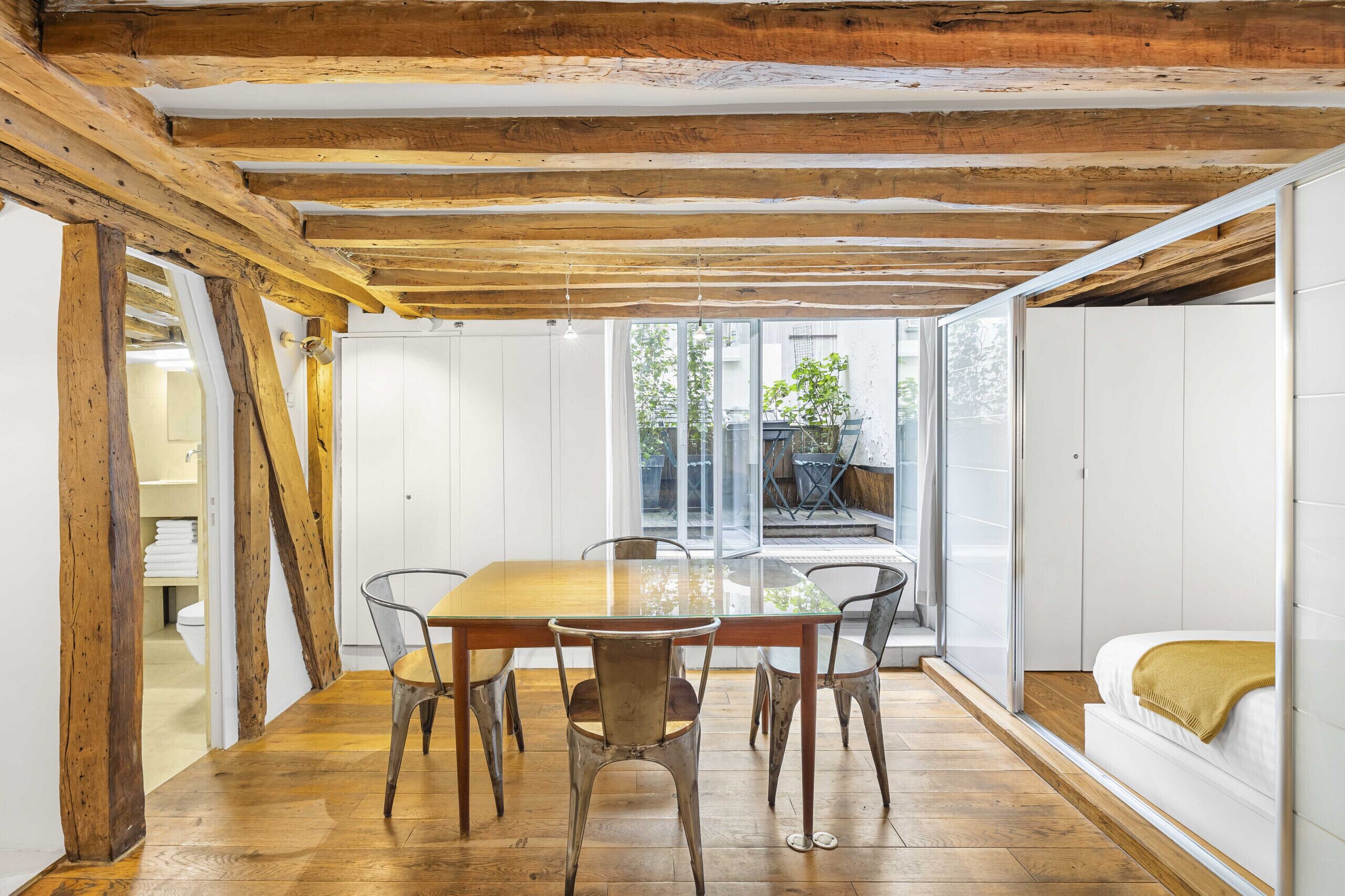 Een eetgedeelte met een houten tafel en stoelen, een glazen scheiding en uitzicht op het omliggende landschap.