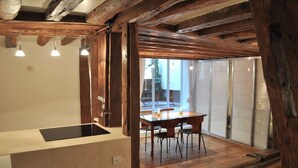 Eine moderne Küche mit Holzbalkendecke, einer Kochinsel und einem Essbereich mit Tisch und Stühlen.