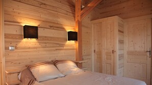 Ein Schlafzimmer einer Holzhütte mit einem Bett, Nachttischen und zwei Wandleuchten.