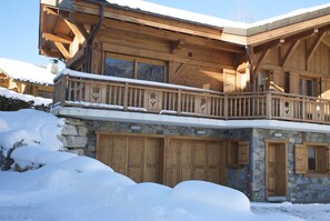 Un chalet en bois doté d’un balcon et d’une façade en pierre, entouré de neige.