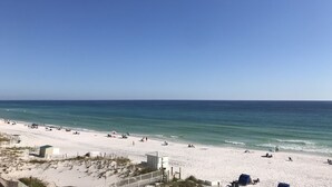 Une plage avec un ciel dégagé, un rivage sablonneux et quelques parasols.