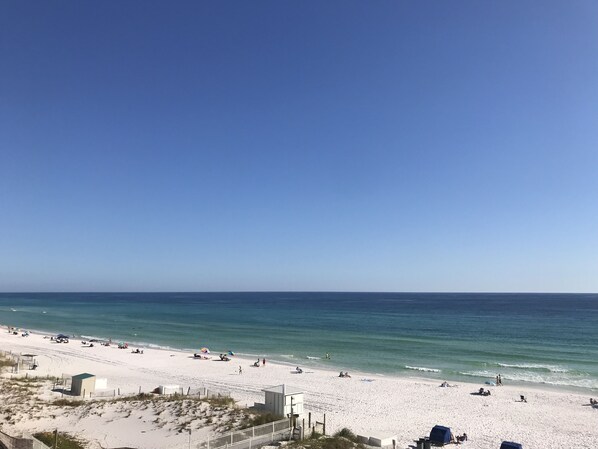 A beach with a clear sky, sandy shore, and a few umbrellas.
