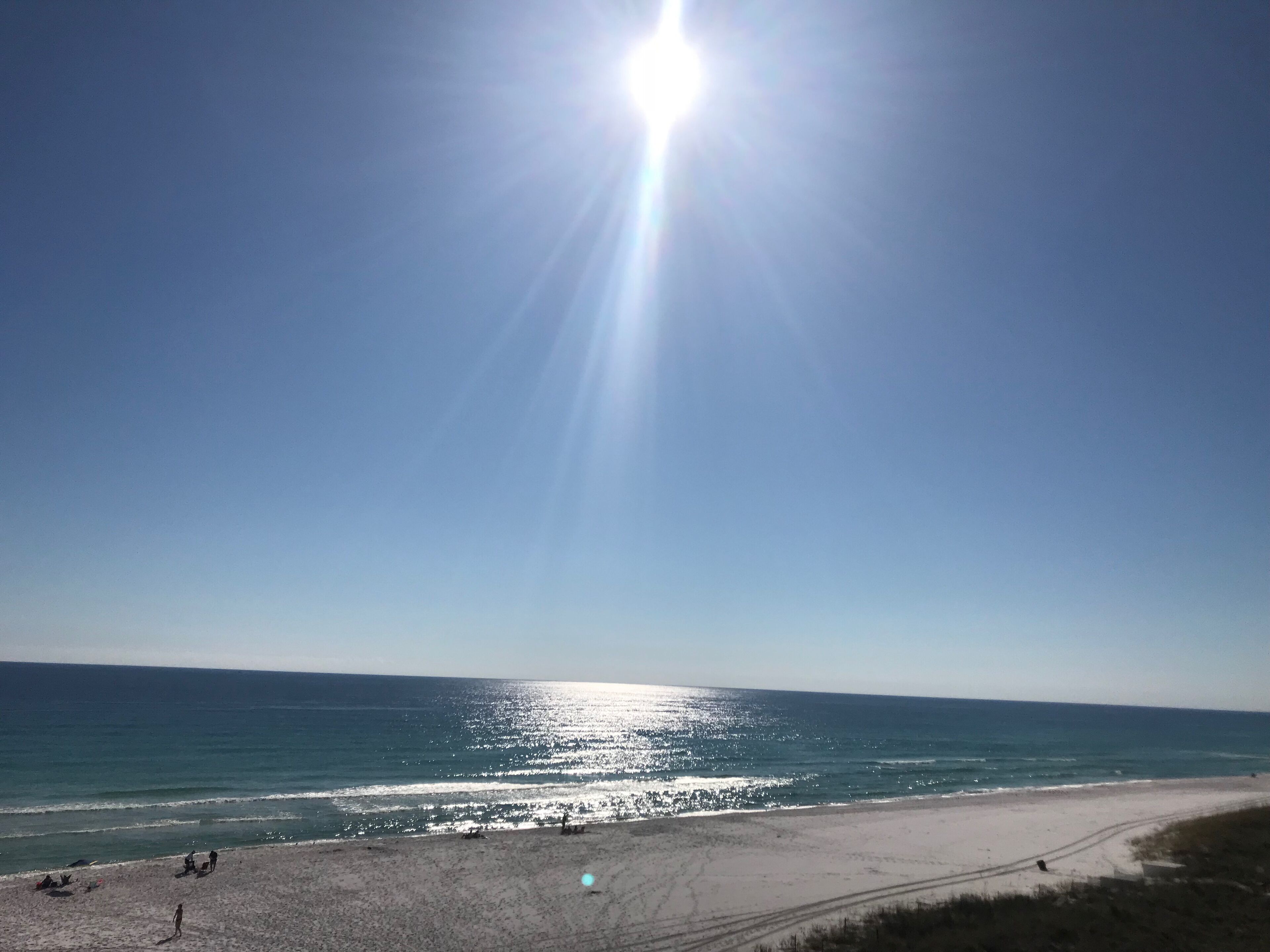 Ein Strand mit blauem Himmel und strahlender Sonne.